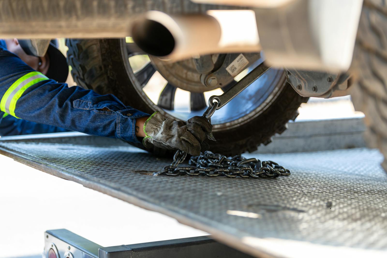 Mechanic securing a vehicle on a service platform with a chain for safe towing.